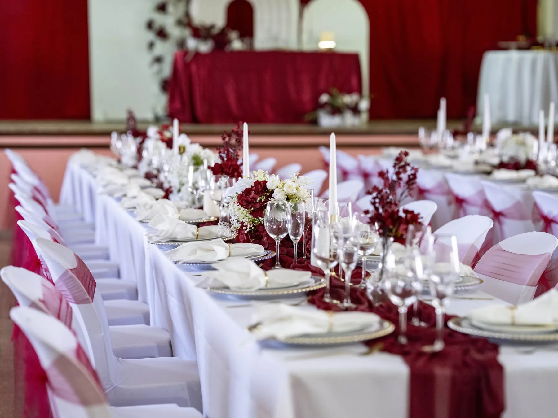 Mesa comprida de casamento em bordeaux e branco, com velas